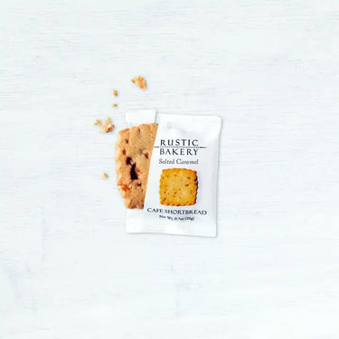 A Salted Caramel Shortbread Cookie 🧈 – Buttery, Golden & Irresistibly Simple, partially unwrapped from its white packaging, rests on a light surface with a few crumbs—an inviting single-serve cookie moment.